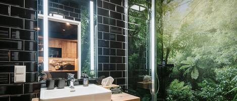 A bathroom with a black tiled wall, a white sink, and a shower with a glass door.