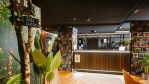 A reception area with a wooden floor, a round rug, a reception desk, and a self-check-in sign. - Rioca Vienna Posto 2 (Vienna)