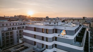 A multi-story building with a rooftop terrace, a visible logo, and a cityscape in the background. - Rioca Vienna Posto 2 (Vienna)