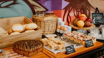 Eine Bäckertheke mit verschiedenen Backwaren, darunter ein schokoladenglasierter Kuchen, Gebäck und eine Obstschale.