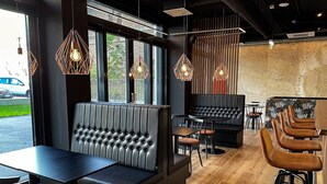 A modern restaurant interior with black upholstered booths, wooden tables, and bar stools. - Rioca Vienna Posto 2 (Vienna)