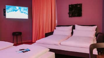 Ein Hotelzimmer mit einem Bett, einem kleinen Tisch, einem Sessel, einem Fernseher und einem Vorhang.