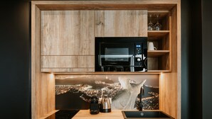A kitchen with a built-in microwave, coffee maker, and sink, with a cityscape view through a wooden frame. - Rioca Vienna Posto 2 (Vienna)