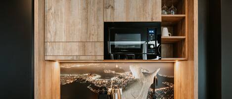 A kitchen with a built-in microwave, coffee maker, and sink, with a cityscape view through a wooden frame.