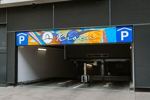 Entrada de um estacionamento com uma placa colorida acima.
