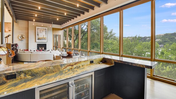 A modern kitchen with a marble countertop, large windows, and a fireplace. - Above Waterfalls I Premier | Party Dock I Pool I Theater I Luxury I Services (Austin)