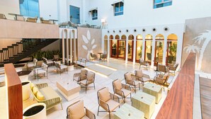 A spacious indoor area with multiple seating arrangements, a staircase, and a view of the outside. - Hasanah Suites for Serviced Apartments. (Madinah)