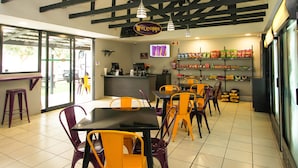 Interior de un restaurante con mesas, sillas, una barra y un letrero que dice 'Welcome'.