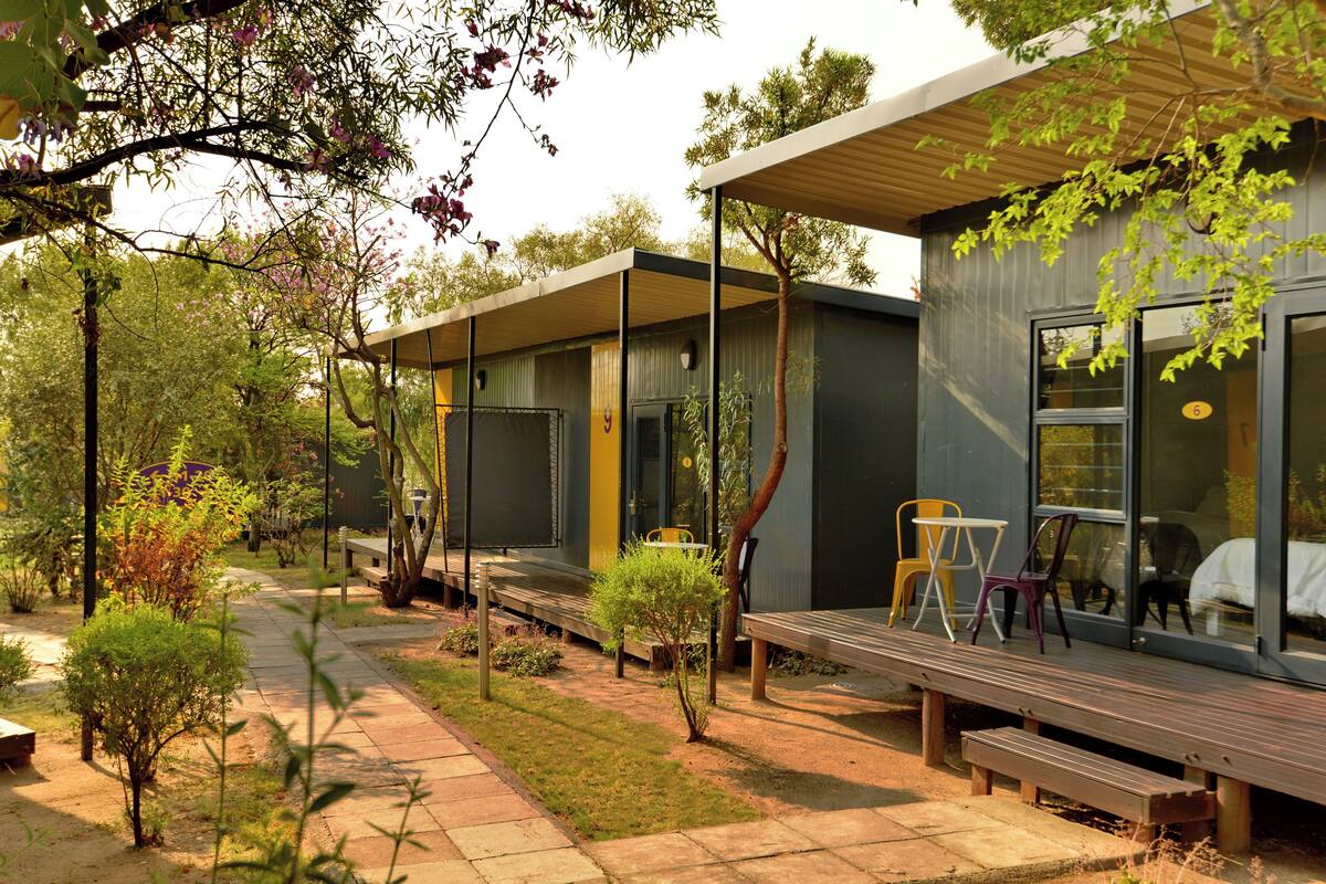 A modern building with a covered patio area, outdoor seating, and a pathway leading to the entrance.