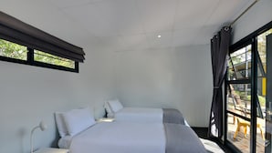 Un dormitorio con cama, mesita de noche y ventana con cortinas.