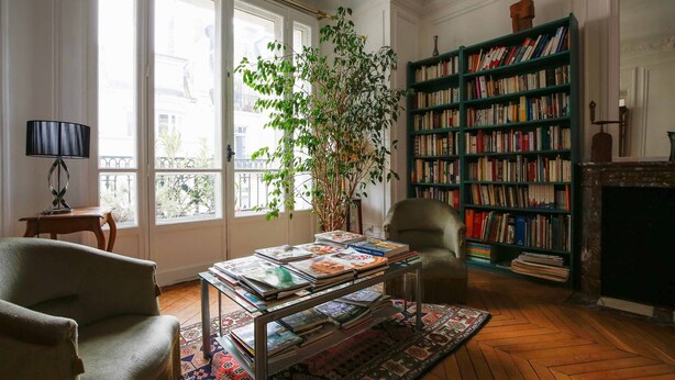 Un salon chaleureux avec une bibliothèque, une cheminée et une grande fenêtre.