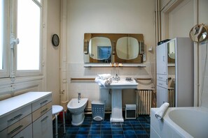 Ein Badezimmer mit einer Bidet-Funktion, einem Waschbecken, einem Spiegel, einer Heizung und einer Badewanne.