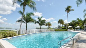 A swimming pool with clear blue water, surrounded by palm trees and a white fence. - GORGEOUS UPSCALE LONGBOAT KEY CONDO OFFERS BAYFRONT VIEWS!! (Longboat Key)