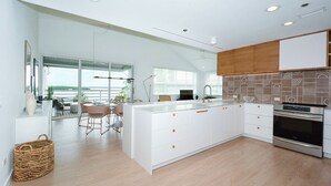 A modern kitchen with white cabinetry, a large island, and a view to the outside. - GORGEOUS UPSCALE LONGBOAT KEY CONDO OFFERS BAYFRONT VIEWS!! (Longboat Key)