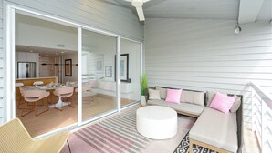 A modern living room with a glass sliding door leading to a kitchen, a ceiling fan, and a seating area with a sofa and ottoman. - GORGEOUS UPSCALE LONGBOAT KEY CONDO OFFERS BAYFRONT VIEWS!! (Longboat Key)