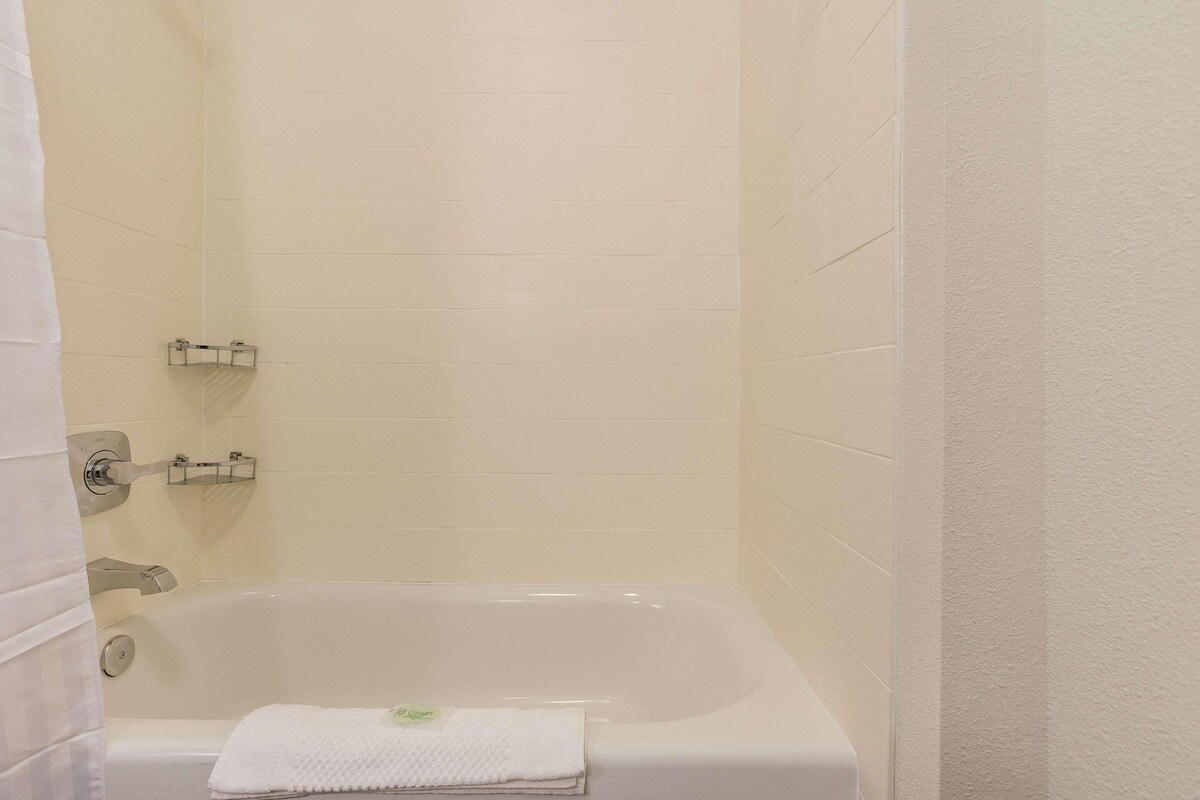 A bathroom with a white bathtub, a towel rack, and a shower curtain.