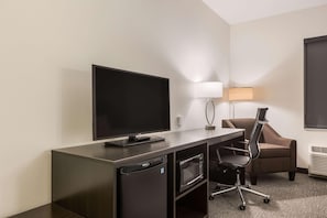 A hotel room with a flat-screen TV, a desk with a lamp, a microwave, and a chair. - Sleep Inn & Suites Webb City (Webb City)