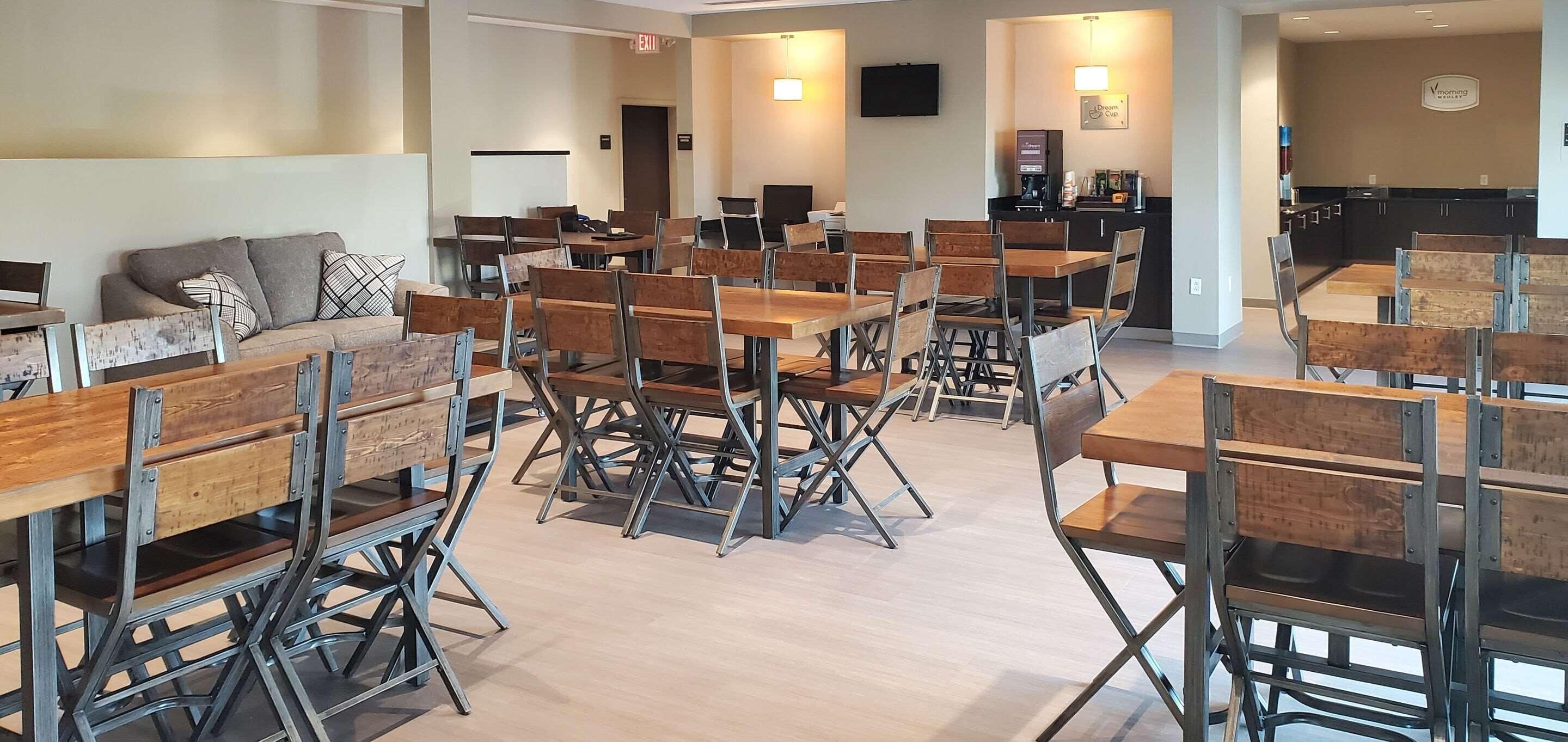 A modern hotel lobby with multiple seating areas, including a sofa and tables with chairs.