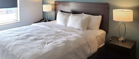 A neatly made bed with white linens, a wooden headboard, and two bedside lamps on nightstands.