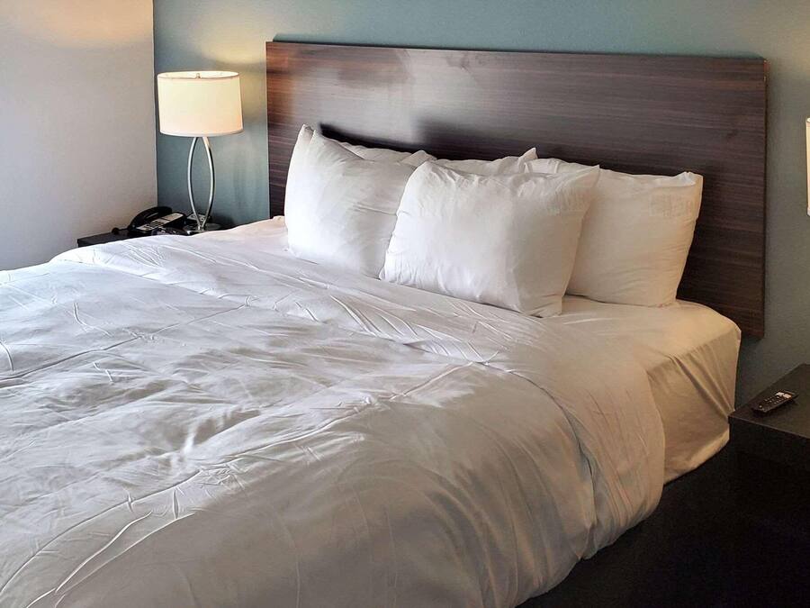A neatly made bed with white linens, a wooden headboard, and two bedside lamps on nightstands.