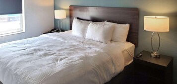 Una cama bien tendida con sábanas blancas, un cabecero de madera y dos lámparas de noche en mesitas.