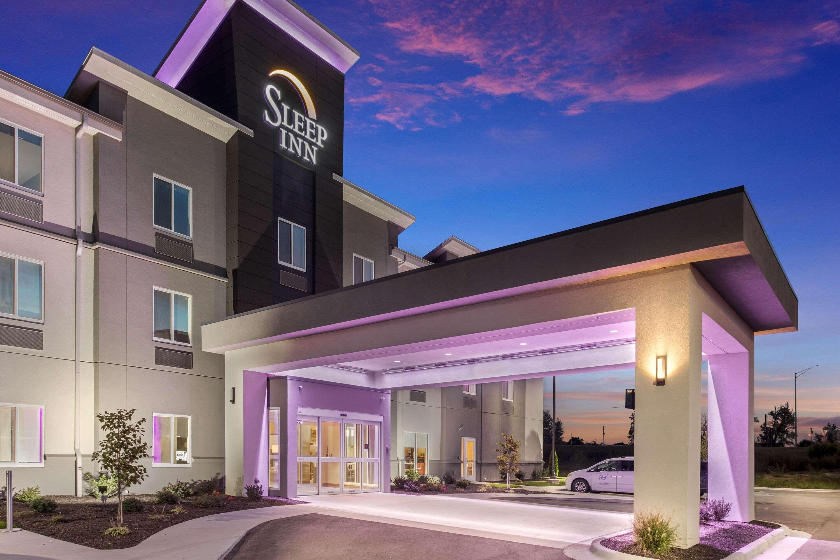 A modern hotel with a prominent sign, a covered entrance, and a well-lit facade.