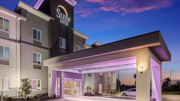 A modern hotel with a prominent sign, a covered entrance, and a well-lit facade.