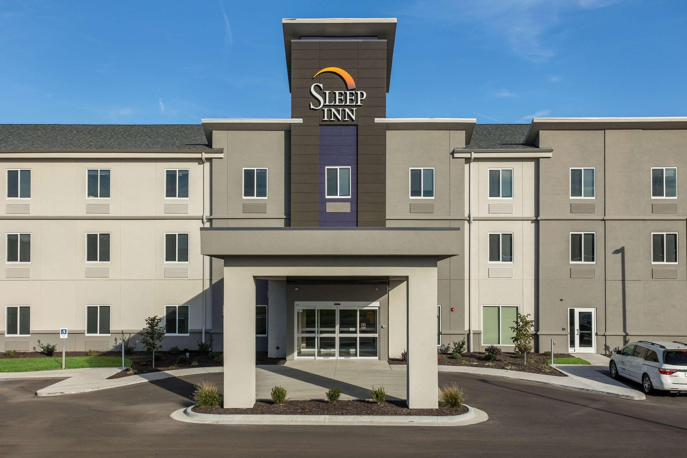A Sleep Inn hotel with a modern facade, a central entrance, and a parking area.