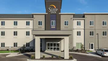 A Sleep Inn hotel with a modern facade, a central entrance, and a parking area.