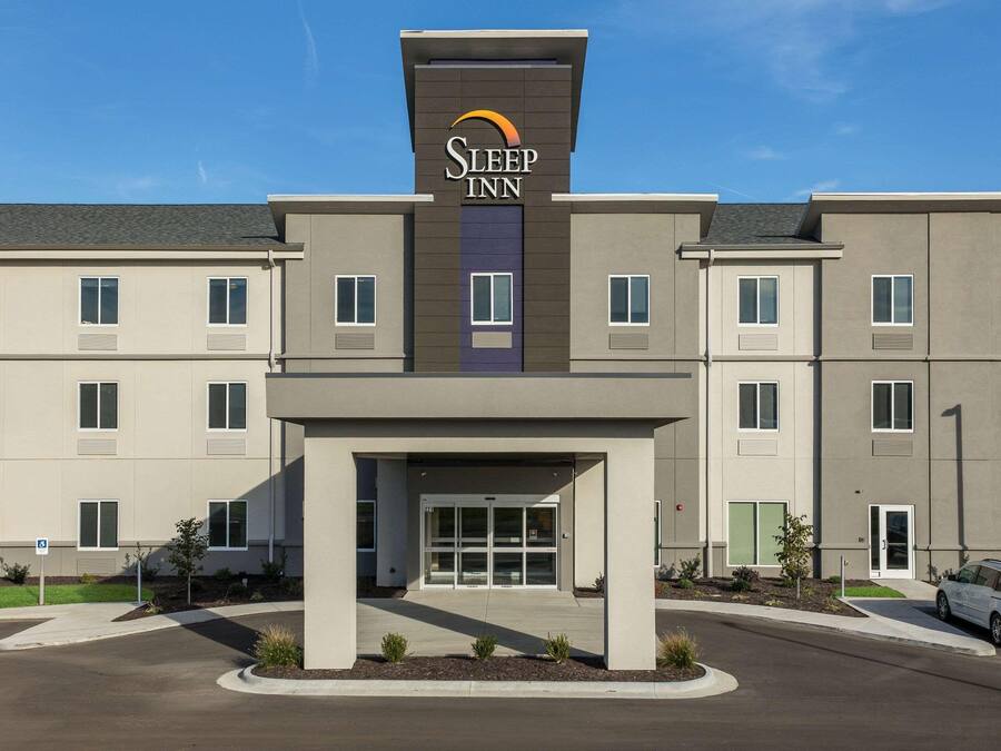 A Sleep Inn hotel with a modern facade, a central entrance, and a parking area.