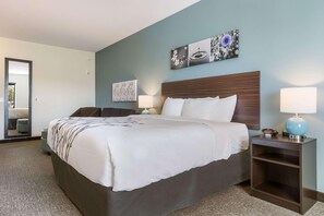 Een hotelkamer met een groot bed, twee nachtkastjes, een spiegel en kunst aan de muur.