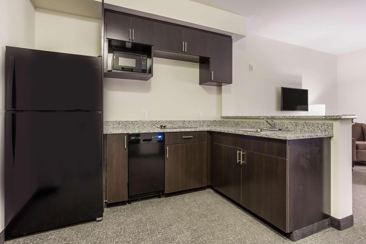 A kitchen with dark wooden cabinets, a black refrigerator, a microwave, and a dishwasher.