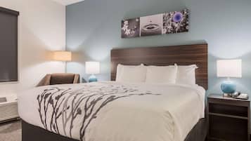A hotel room with a large bed, two bedside tables with lamps, a wall-mounted artwork, and a window with blinds.