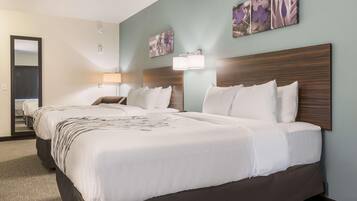 A hotel room with two beds, a large mirror, and artwork on the walls.