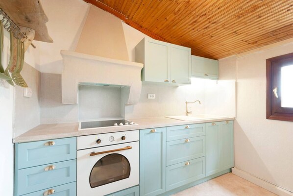 A kitchen with light blue cabinets, a white oven, and a wooden ceiling.