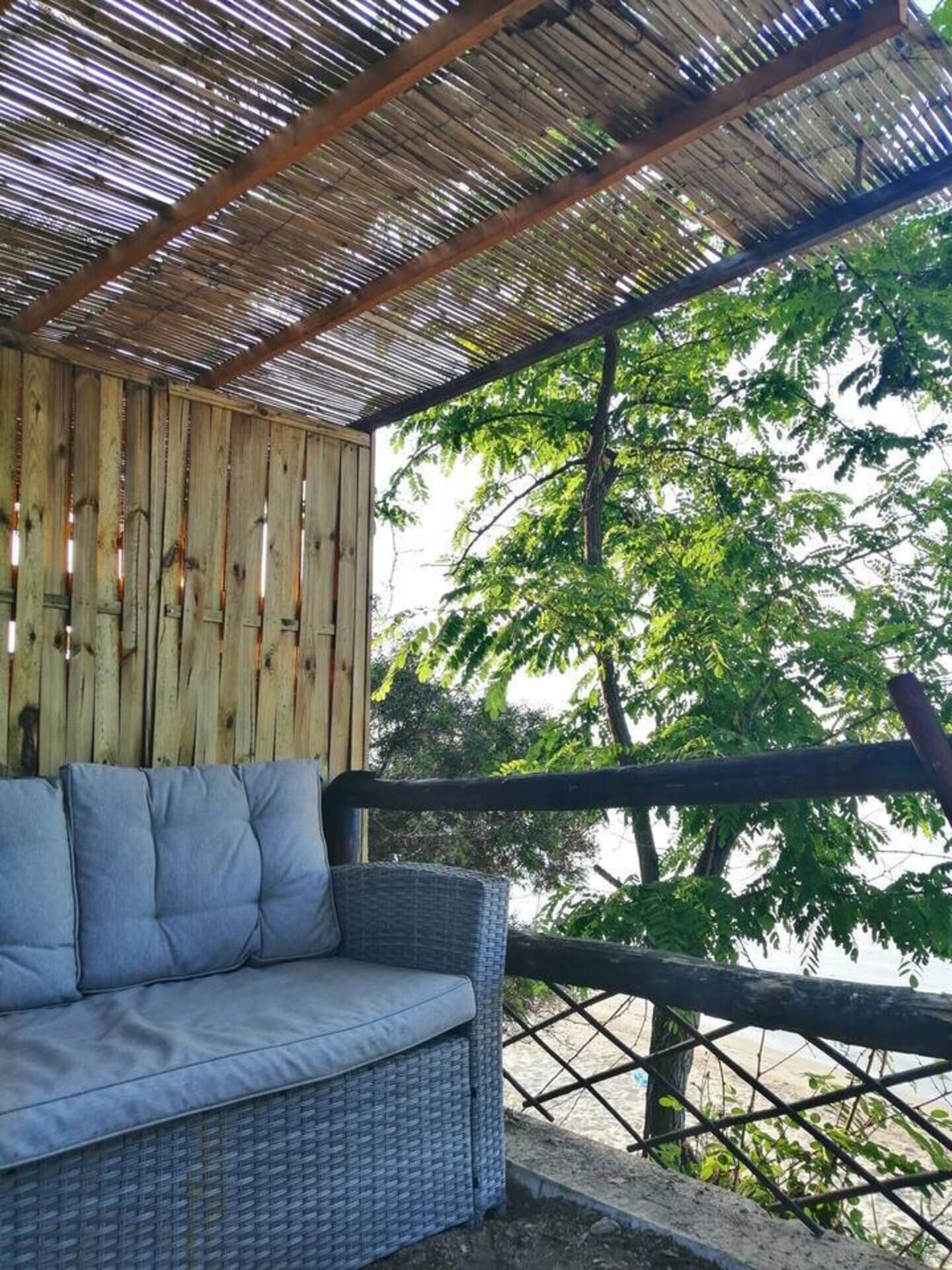 Un espacio de estar techado al aire libre con sofá de mimbre y pared de madera.