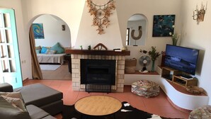 Un salon avec une cheminée, un canapé, une télévision et des objets de décoration.