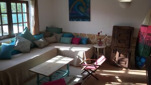 Un salon confortable avec un canapé, une table et une chaise. Il y a un tableau au mur et une fenêtre avec des rideaux.