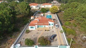 Vue aérienne d’un quartier résidentiel avec des maisons, une piscine et un espace de stationnement délimité par une clôture.