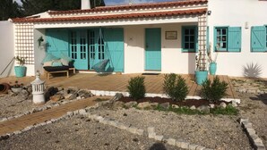 Un bâtiment blanc avec des volets turquoise et un toit recouvert de tuiles.