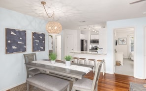 A dining area with a wooden table, bench seating, and a hanging light fixture.