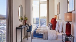 Een moderne hotelkamer met een groot bed, een bureau en uitzicht op de stad.