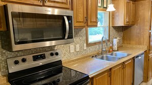 A kitchen with wooden cabinets, a stainless steel microwave, a stove, and a sink.