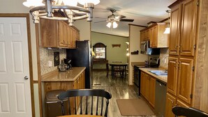 A kitchen with wooden cabinets, a dining table, chairs, a ceiling fan, and a microwave.