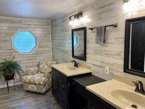 Une salle de bain moderne avec un grand miroir, deux lavabos et une fenêtre donnant sur un beau paysage.