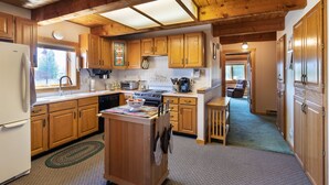 Una cocina con armarios de madera, una isla central y un comedor con una silla.