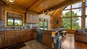 Una cocina amplia con armarios de madera, encimeras de granito y un gran ventanal con vistas al exterior.