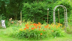 A garden with a wooden arbor and a stone wall. - Vacation apartment "Biene" in the listed Krahne art estate (Kloster Lehnin OT  Krahne)