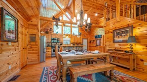 A log cabin interior with a dining table, wooden walls, and a chandelier. - TEXAS 2 STEP Luxury Log Cabin at the Entrance to Beavers Bend State park (Broken Bow)