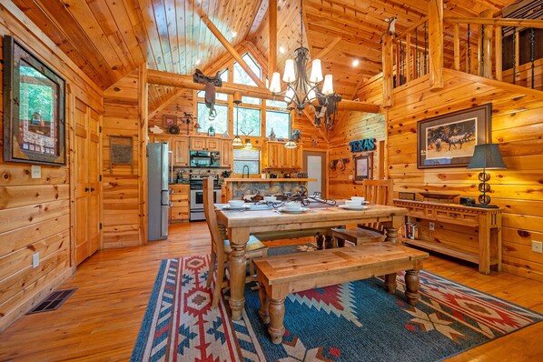 L’intérieur d’une cabane en rondins, avec une table à manger, des murs en bois et un lustre.